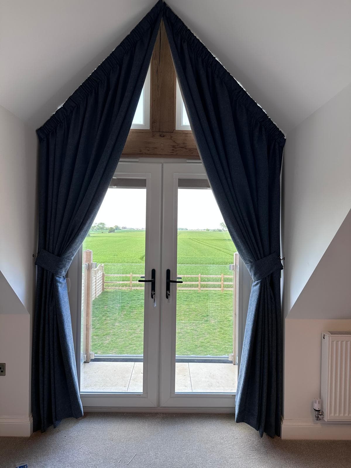 Triangular bedroom window framed by dark blue curtains